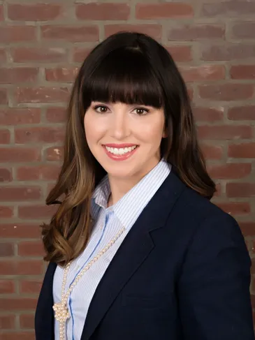 A woman with long hair and bangs wearing a suit.